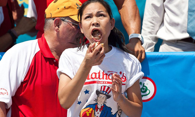 Người phụ nữ châu Á cố gắng ăn nhồi nhét trong cuộc thi ăn hot-dog nhanh nhất được tổ chức tại Mỹ năm 2013